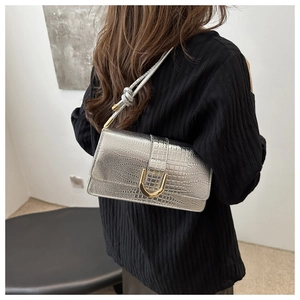 Détail du sac à bandoulière argenté à motif crocodile avec boucle en métal doré
