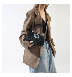 Détails d'un sac à main noir brillant avec bords ondulés et boucle carrée en cristaux