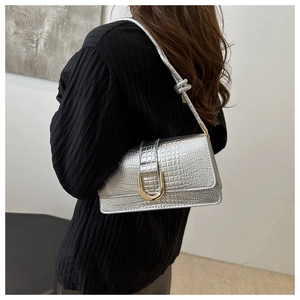 Détail du sac sous le bras argenté à motif crocodile avec boucle en métal doré en forme de U
