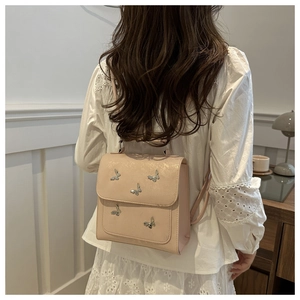 Detail of light pink mini backpack with silver butterfly accents shown on model back