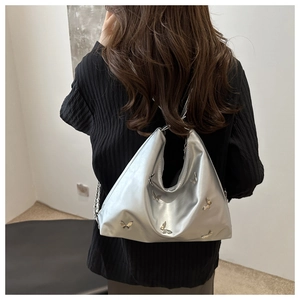 Silver metallic butterfly tote bag with chain strap shown on model's shoulder