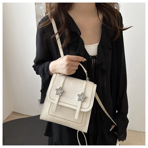 Detail of cream white leather handbag with silver star studs and refined stitching