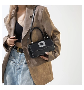 Détail du sac bandoulière noir avec boucle sertie de cristaux et bord de rabat festonné