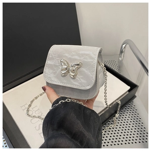 Macro detail of silver butterfly clasp on gray marble texture mini crossbody chain bag