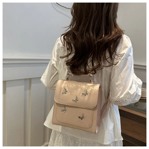 Detail of light pink PU leather backpack with silver butterfly metal decorations