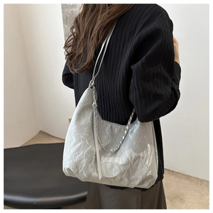 Detail of silver metallic tote bag with chain strap and unique pleated texture design