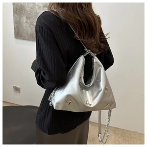 Detailed view of silver metallic bag with 3D butterfly accents and chain strap