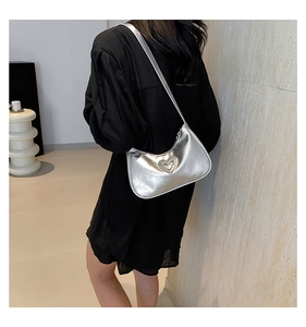 Silver baguette shoulder bag with diamond heart accent styled on a black dress