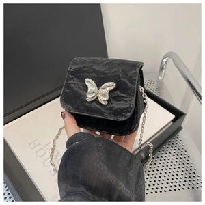 Detail of silver butterfly buckle and crinkled texture on a black crossbody bag
