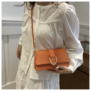 Détail du sac à bandoulière orange à motif crocodile avec une boucle en U dorée