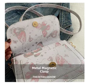 Close-up of the golden magnetic buckle and butterfly print on pink faux leather bag