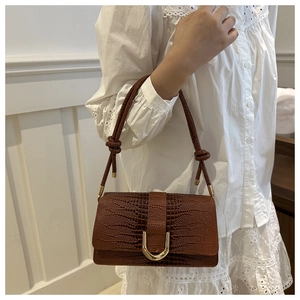 Gros plan sur le sac en cuir gaufré crocodile marron avec boucle en métal doré en forme de U