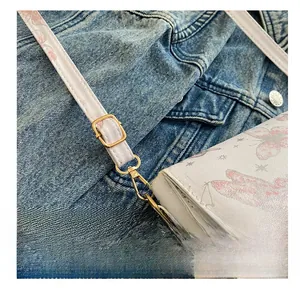 Detail of adjustable golden buckle on textured PU leather crossbody bag with butterfly prints