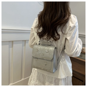 Silver backpack with butterfly metal accents shown on person for style and scale