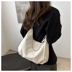 Detailed close-up of a large beige hobo bag with a stylish metal chain shoulder strap