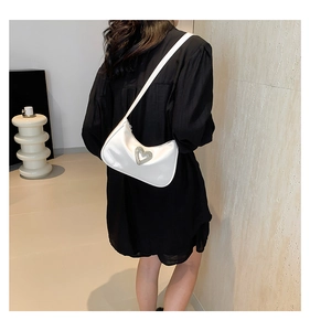Detailed view of white baguette bag with rhinestone heart on a black dress model