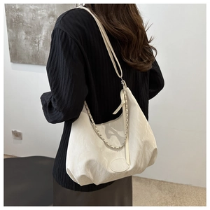 Detail of hobo bag with textured cream leather, decorative chain and shoulder strap