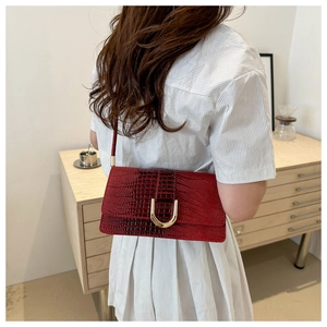 Détail d'un sac à main rouge motif crocodile avec une élégante boucle en métal doré en U
