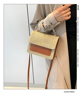 Close-up of woven straw bag with pearl handle and leather flap detail for summer