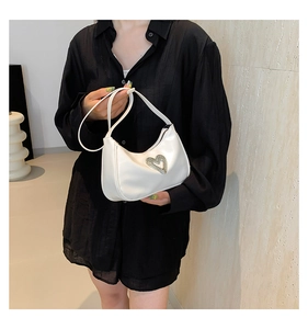 Close-up of white leather hobo bag featuring a sparkling rhinestone heart buckle