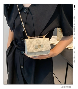 Detail of beige straw crossbody bag with golden chain strap and V-shaped weave texture