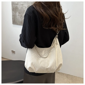 Detail of cream hobo bag showing marble texture fabric and metal chain strap
