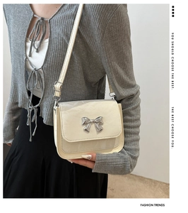 Sac bandoulière crème chic avec boucle nœud argenté porté avec un cardigan gris