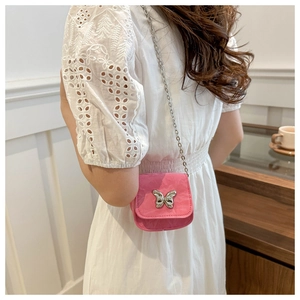 Mini pink chain crossbody bag with silver butterfly charm on white summer dress