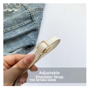 Detail of white lychee leather shoulder strap with gold buckle and stitching accents