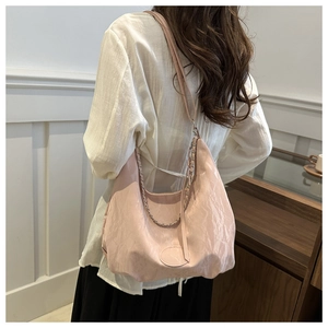 Pink hobo bag with pleated texture and chain detail shown in a casual lifestyle setting