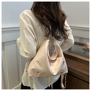 Detailed view of apricot pink shoulder bag with silver butterfly charms and chain strap