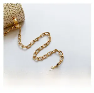 Detail view of the golden metal chain strap on a stylish summer woven straw bag