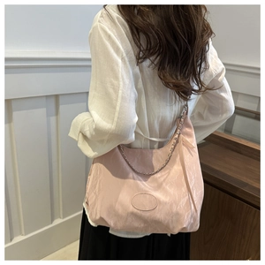 Detail of pink nylon dumpling bag with metallic chain strap and textured fabric