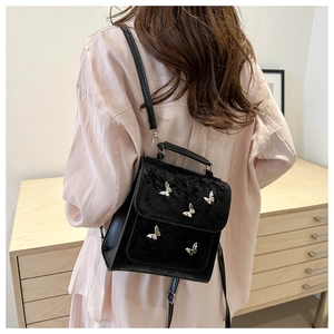 Detail of black mini butterfly backpack with silver metallic accents worn on shoulder