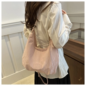 Detail of light pink pleated nylon hobo bag with gold chain and leather strap