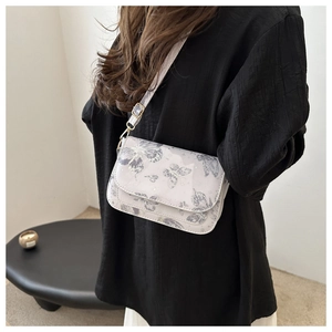 Detail of crossbody bag with butterfly print and adjustable strap on black shirt