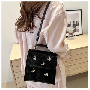 Detail shot of black matte crossbody bag featuring silver butterfly metal ornaments