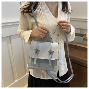 Close-up of light blue crossbody bag with metal star studs and gold rivet details