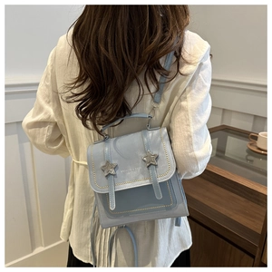 Detail of light blue leather backpack featuring star hardware and fashion lettering