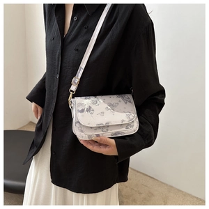 Detail of light gray butterfly print crossbody bag with adjustable strap and metal hardware