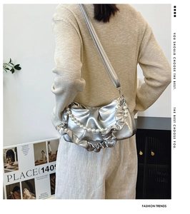 Détail du sac argenté métallisé à volants avec grande chaîne en perles sur l'épaule