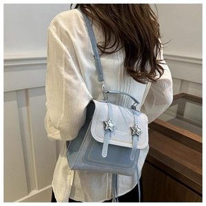Close-up of light blue fashion backpack with silver stars and adjustable straps on model