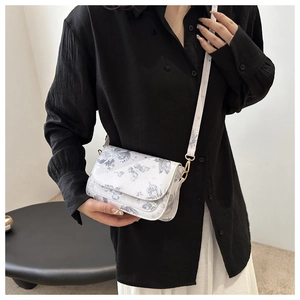 Close-up of white crossbody bag with blue butterfly print and golden metal hooks