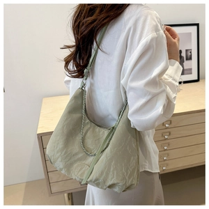 Close-up of mint green pleated hobo bag with leather chain strap on a model shoulder