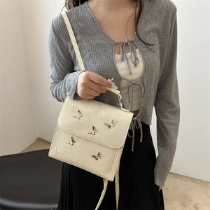 Elegant beige butterfly handbag with metal accents shown as a stylish crossbody bag