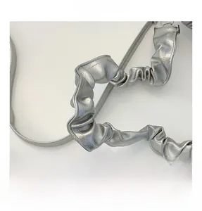 Close-up of the silver metallic shoulder bag showing the ruched handle and pleated details