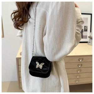 Detailed back view of a black velvet mini crossbody bag with silver butterfly clasp and chain