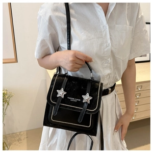 Detail of black velvet shoulder bag with silver stars and white bead accents on leather