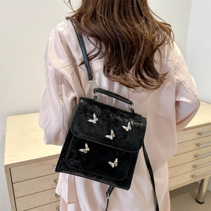 Elegant black glossy shoulder bag with silver butterfly accents shown on a model