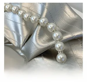 Detailed shot of silver metallic pleated fabric with luxury pearl and rhinestone beads